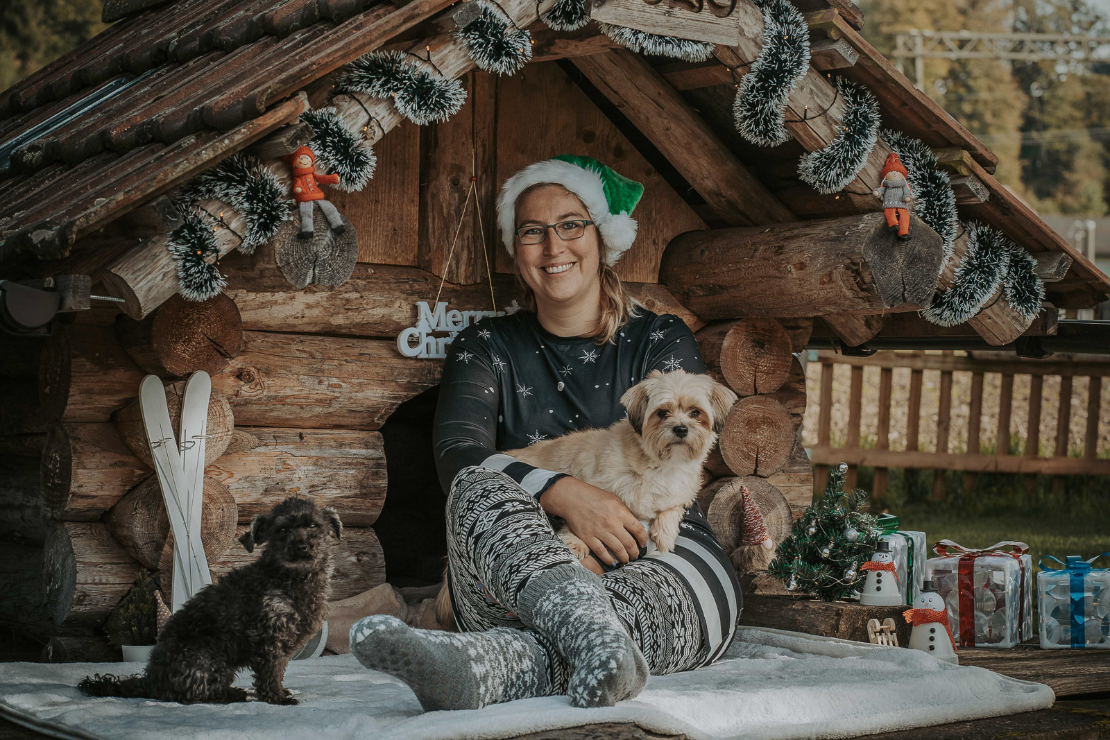 199 - lisamariekurth-hundefotografin-weihnachten-195 Hundefotografie zu Weihnachten: Besitzerin und ihre zwei Hunde vor einer weihnachtlich geschmückten Holzhütte.
